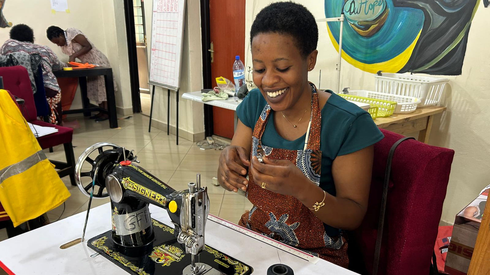 A DuHope artisan smiling while working at a sewing machine